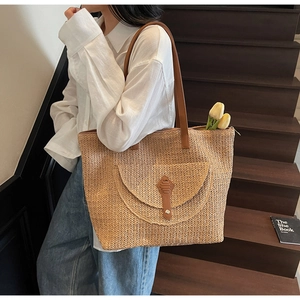 Grand sac cabas en paille avec poche frontale en cuir marron et lanières sur fond lifestyle