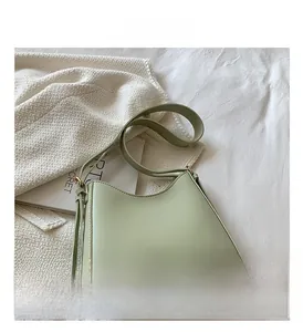 Detail of sage green matte leather shoulder bag with gold hardware and fine stitching