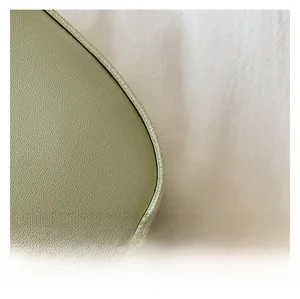 Detailed macro view of light green lychee pattern leather texture with fine white stitching
