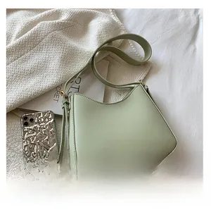 Flat lay of mint green leather underarm bag with gold hardware on knit fabric