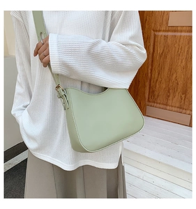 Outdoor shot of light green leather crossbody bag with adjustable strap and gold hardware
