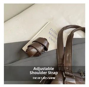 Close-up of adjustable leather shoulder strap with silver metal buckle on brown tote bag