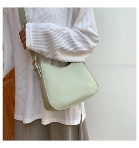 Detail of light green hobo bag featuring adjustable strap and elegant gold buckle