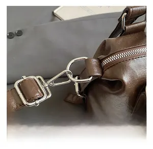 Macro detail of dark brown textured tote bag with silver metal hooks and zipper hardware