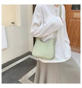 Modern mint green crossbody bag with adjustable wide strap worn by a model in soft light