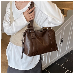 Vue détaillée de la texture en cuir marron brillant et boucle argentée du sac à bandoulière