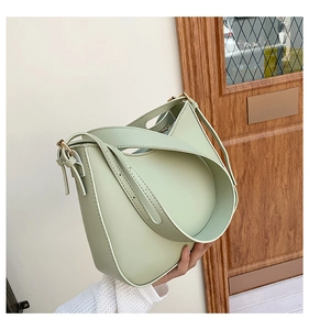 Detail of the mint green PU leather handbag featuring a curved design and wide shoulder strap