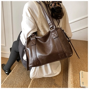 Detail shot of a dark brown oil-wax leather tote bag showing crossbody strap and silver buckle