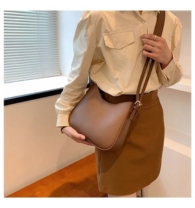 Detail of adjustable strap and gold buckle on a retro brown leather shoulder bag