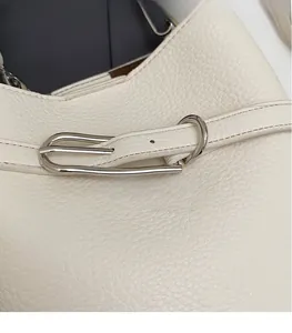 Gros plan sur le sac en cuir grainé blanc avec boucle en métal argenté poli