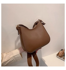 Detail of a brown vintage saddle bag featuring smooth texture and gold metal buckle strap