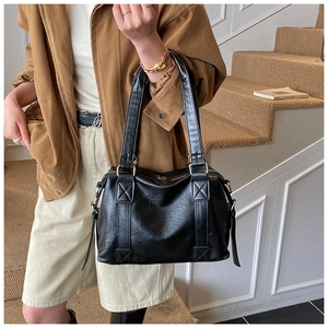 Detailed view of black faux leather tote bag with glossy texture and side zipper detail