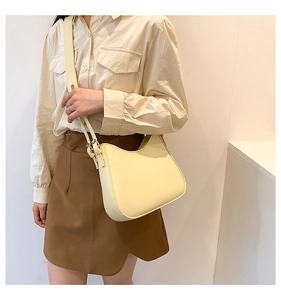 Pale yellow hobo bag with smooth matte finish and adjustable strap shown on model
