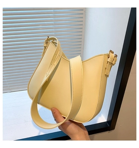 Close-up of pale yellow crescent underarm bag with smooth leather texture and gold buckle