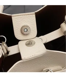 Détail d'un sac seau en cuir grainé blanc avec fermoir magnétique argenté et doublure brune