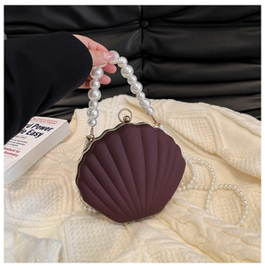 Detail of shell-shaped burgundy evening bag with pearl handle and metal ball clasp