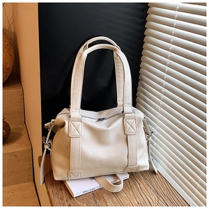 Close-up of a minimalist cream white faux leather tote bag with top handle and zipper detail