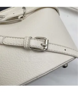 Gros plan sur la boucle métallique argentée et le cuir grainé de ce sac seau élégant