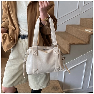 Détail de la texture cuir grainé blanc cassé et coutures sur le grand sac à bandoulière