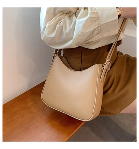 Minimalist beige leather crescent bag shown in a warm, lifestyle aesthetic setting