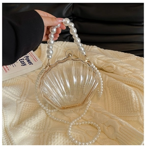 Detailed macro view of clear shell-shaped acrylic clutch with elegant pearl handle strap