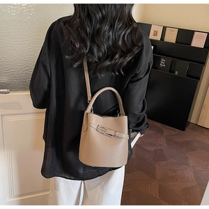 Détail de la texture d'un sac seau en cuir marron grainé porté par un mannequin