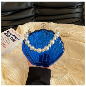 Detailed close-up of blue acrylic shell clutch with pearl handle and metal clasp