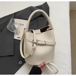Détail d'un sac seau blanc crème en cuir grainé avec bandoulière et finitions métalliques