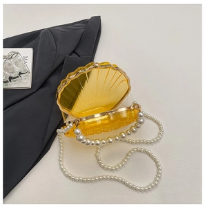 Detailed close-up of shell-shaped acrylic evening bag with pearl chain and gold metal frame