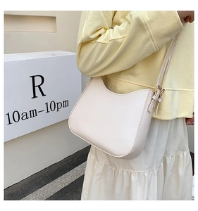 Detailed side view of a cream half-moon shoulder bag with adjustable strap and metal hardware