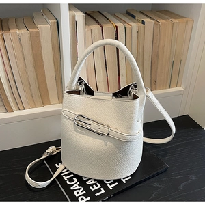 Détail du sac seau blanc avec texture litchi et fermoir métallique sur étagère