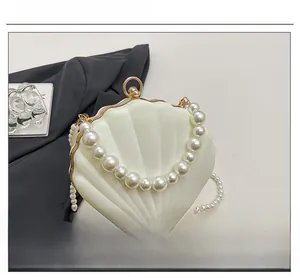 Detail view of shell-shaped ivory evening bag with pearl handle and gold frame