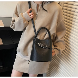 Détail d'un sac seau en cuir noir grainé avec boucle argentée et bandoulière amovible