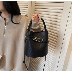Détail du sac seau en cuir noir grainé avec boucle argentée et bandoulière réglable