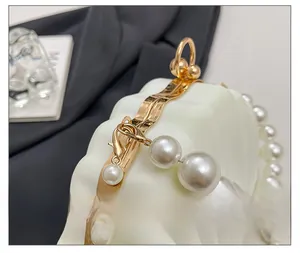 Detail of golden wavy metal frame and lobster clasp on shell-shaped evening bag