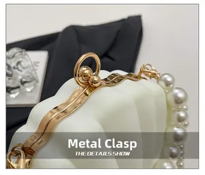 Detail of elegant gold metal clasp and white pearls on wavy textured evening clutch