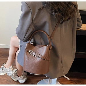 Détail du sac seau en cuir marron avec boucle métallique et bandoulière réglable