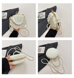 Macro detail of shell-shaped acrylic evening clutch with pearl handle and gold metal trim