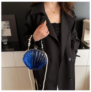 Detail of dark blue shell-shaped evening bag with pearl handle and ribbed texture