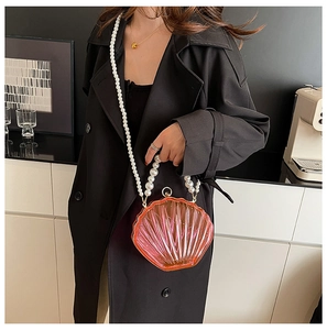 Detailed view of pink shell-shaped acrylic clutch with elegant pearl strap and metal clasp