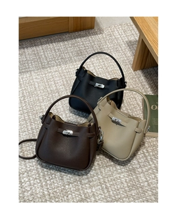 Gros plan de trois sacs seaux en cuir grainé noir, café et beige avec fermoir en métal