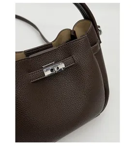 Detailed close-up of dark brown lychee grain leather handbag with silver rotating lock