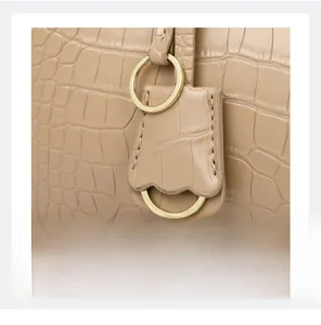 Detail of embossed crocodile pattern on beige leather tote with golden ring hardware
