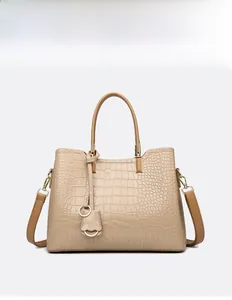 Detail of beige embossed crocodile pattern tote bag with gold-tone hardware and straps