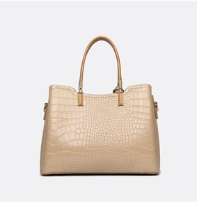 Detailed view of beige tote bag with crocodile pattern and golden metal buckles