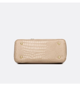Close-up of croc-embossed leather handbag base with protective gold metal feet