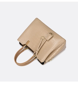 Close-up of beige crocodile pattern handbag with elegant gold hardware and dual handles