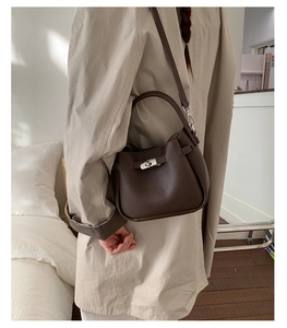 Détail du sac à main en cuir marron foncé avec grain litchi et fermoir rotatif argenté