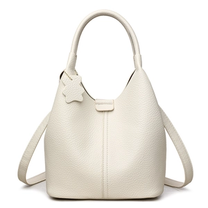 Minimalist beige leather bucket bag with bear charm pendant and textured pebble finish