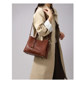 Detail shot of brown crocodile embossed trapezoid handbag with gold hardware studs